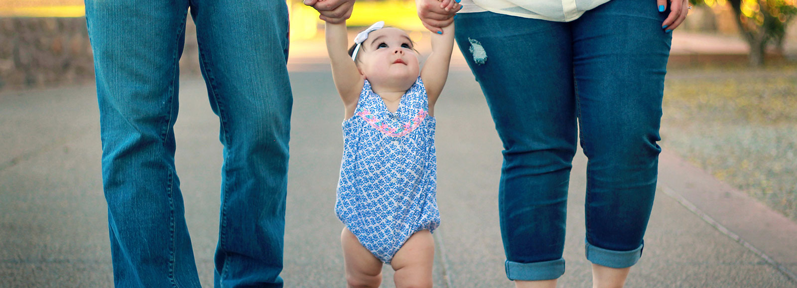 baby standing between parent's legs